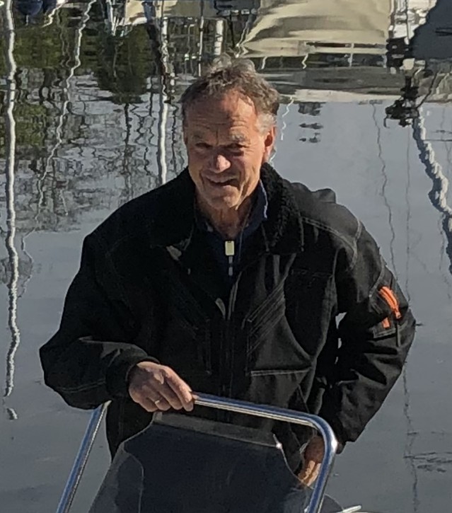 Mann med svart jakke foran vann